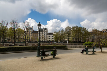 Paris riverbank with benches and people sitting on them