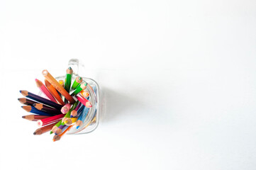Obraz premium Colored pencils placed in a glass on a white background
