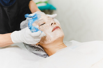 Woman having stimulating facial treatment at professional clinic.