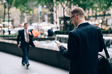 Executive in formal clothes messaging on street