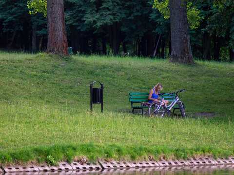 Young girl reading a book in the the green parn frontof the lake