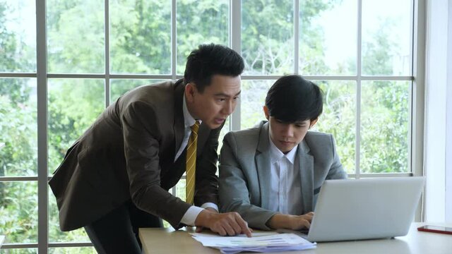 Business & Team work concept. Handheld, medium shot of senior manager coaching, guiding, giving support to junior employee to solve problem.