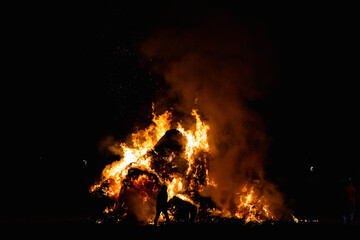 Hot red burning large fire with the black starry night sky. Silhouette of a fireman on the background of a blazing flame
