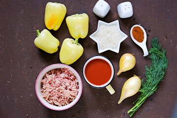 Step by step preparation of stuffed bell peppers, step one, prepared ingredients for cooking on a brown concrete background.
