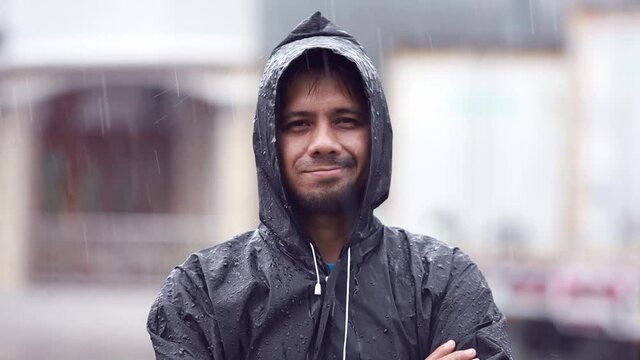 Portrait young Asian man wearing a raincoat in the rains slow motion