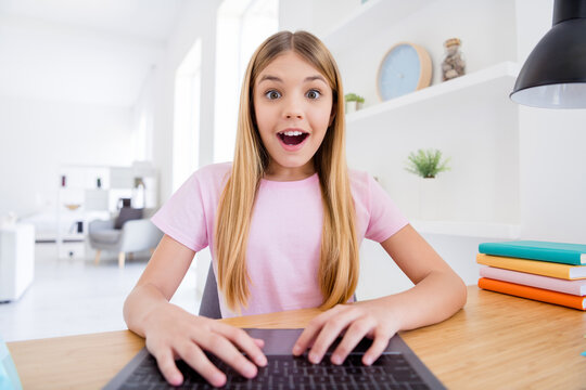 Close up photo of excited little kid girl sit comfort cozy table study remote use laptop video call impressed teacher speak talk good grades exam typing in house indoors