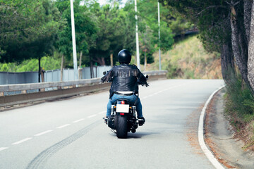 rear view of biker driving motorcycle on the road