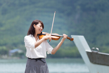 Beautiful asian woman hold violin on nature background, in emotion feeling happy. © montira