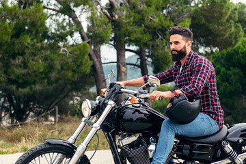 Fototapeta na wymiar bearded man riding motorcycle with helmet off