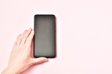  Female hand holding smartphone with blank screen on pink background, closeup. Space for text.
 hand holding phone