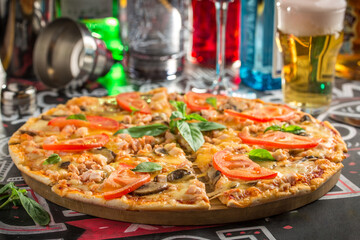 Delicious hot pizza with ham and mushroom and glass of cold beer on bar background