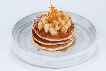 Homemade pancakes dessert with sliced banana, maple syrup drops and sugar powder