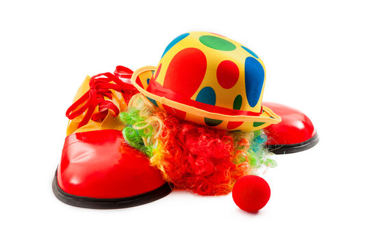 Circus performance and humorous birthday party theme concept with photograph of clown wig in multiple colours, oversized funny shoes, colorful hat and red nose isolated on white background