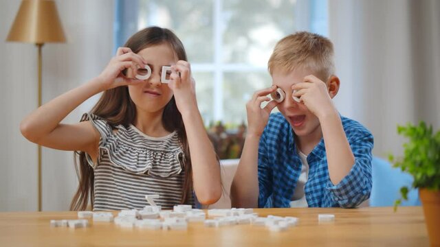 Portrait of happy kids having fun with plastic letters sitting at table