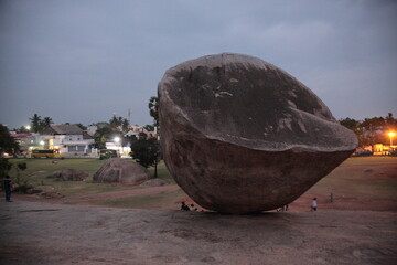 Tourists visiting a gigantic balancing  granite boulder Krishna's Butterball under sunset in Mahabalipuram, Tamil Nadu, India © CYSUN