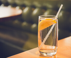 glass of water with a lemon in a green background 