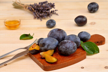 beautiful still life slices of fresh plums on the board and cutlery on the table