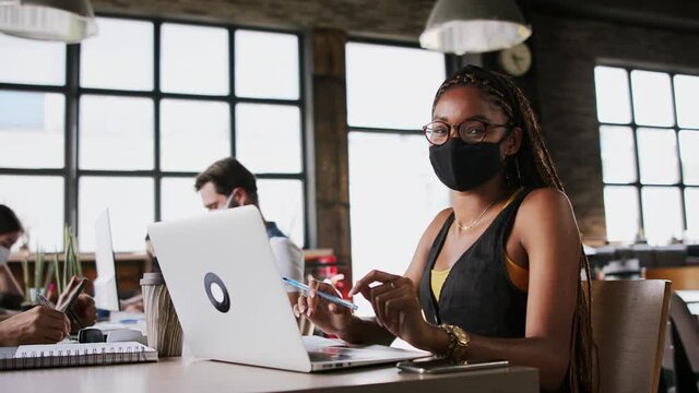 Young business people with face masks working indoors in office, coronavirus concept.