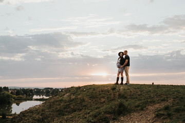 Silhouette of a couple of people on a sunset background. A pregnant woman and her husband are walking in the evening. selective focus