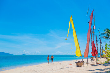 people walk along the beach on the paradise island of koh samui in thailand, white beach and turquoise sea, palm trees and flags on the seashore, vacation in the tropics