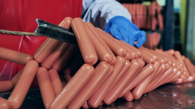 A worker hangs sausages on a rack.