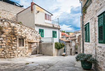 Fototapeta na wymiar Old narrow street on a hill with sandstone houses in Sibenik town, Croatia