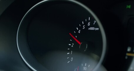 HANDHELD, car driving fast, CU on a car gauge shows rev up toward 5