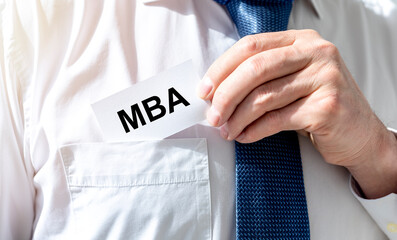 Business education concept. text MBA acronym on white paper card in businessman pocket of white...