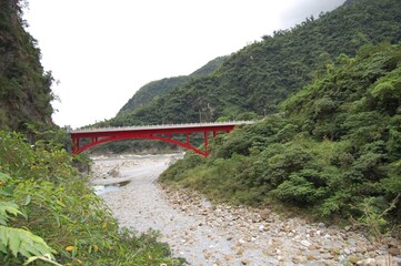 Fototapeta premium Beautiful view of the red bridge over the valley in the forest mountain