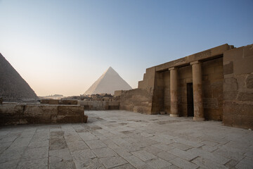 Egyptian temple with pyramid behind at dawn