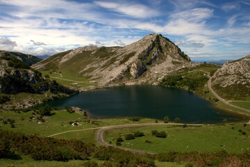 Naklejka na ściany i meble Enol lake, one of the Covadonga lakes, in the Picos de Europa, Asturias, Spain, with blue sky and white clouds in the background.