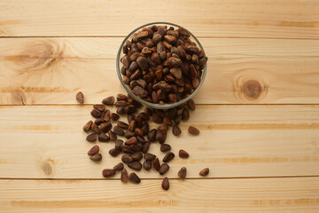 Pine nuts not peeled in a bowl on a wooden background. A useful product for health.