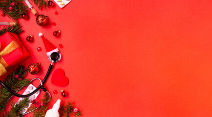 Christmas banner with a Phonendoscope wearing a Santa Claus hat. Nearby lie red balls, a heart, a gift box, branches of a Christmas tree, pills, and medical test tubes. Medical banner concept 