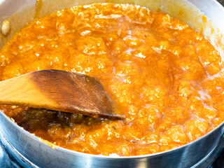 cooking salted butter caramel sauce at home kitchen - boiling melted sugar and butter and cream in steel pan close up