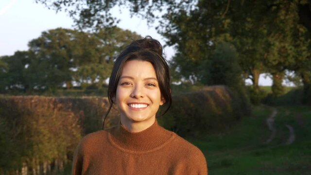 Smiling asian american woman pretty face looking at camera, close up portrait outdoors