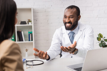 Selective focus of african american doctor looking at patient and pointing with hands