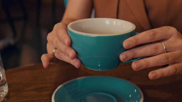 Girl grab coffee in cafe. Pretty young woman enjoying morning drink, female customer in coffee shop with big cup of coffee