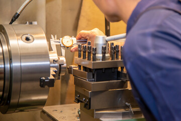 The skill operator measuring the turning parts by Vernier caliper. The metalworking process by...