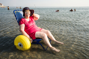 disabled senior lady on a special wheelchair in the sea water