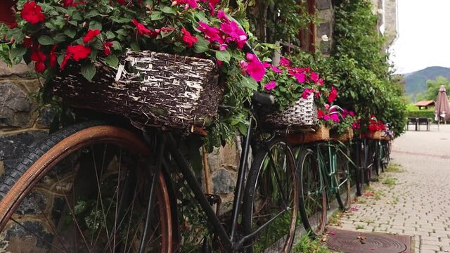 Vintage Bicycles Lined Up Next to a Stone Wall Bar House with Picturesque Flower Baskets in Riano, Spain. Close up, Bokeh, Hiking Trail Tourism