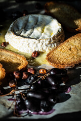 Hot melted Camembert cheese, toasted bread slices, hazelnuts and blue grapes baked in oven.