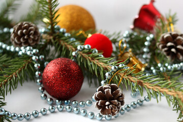 Obraz na płótnie Canvas Glass beads, Christmas balls, fir paws and cones on a white background. New Year's composition - postcard. Selective focus. 