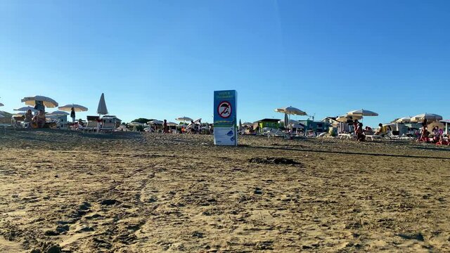 Timelapse of unidentifiable people in the late afternoon on Caorle beach in Veneto, Italy.