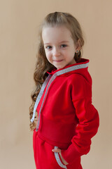 A little girl in a red suit poses on a colored background. Fashionable children's clothing.