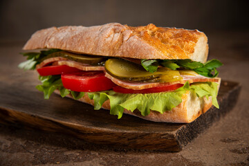 Sandwich with homemade bread, ham, tomatoes, lettuce and pickled cucumber