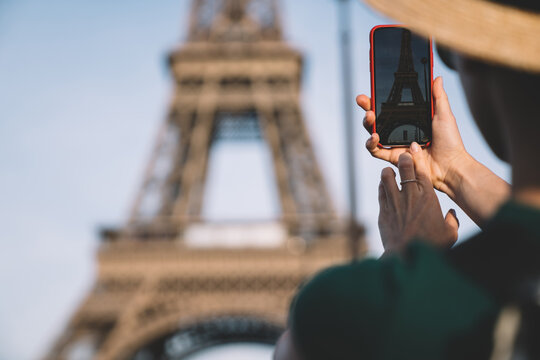 Unrecognizable tourist taking photos of Eiffel Tower