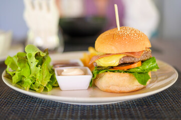 Large of tasty burger with beef, tomato, cheese and lettuce served in a plate