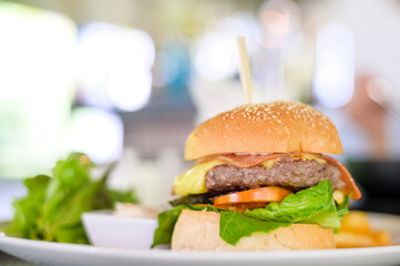 Large of tasty burger with beef, tomato, cheese and lettuce served in a plate