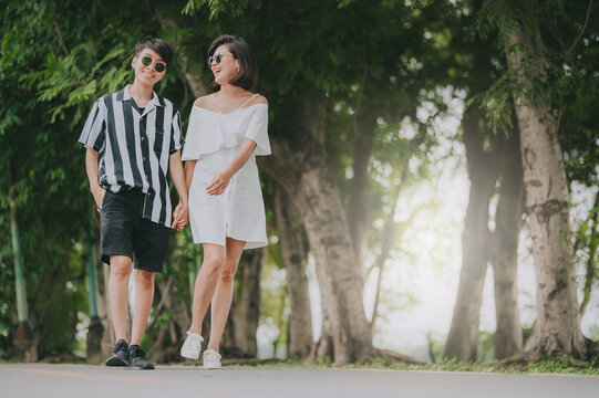 Happy young Asian women LGBT lesbian couple holding hands walking outdoor in the park