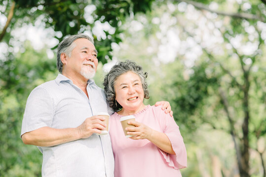 Happy Asian senior older couple drink coffee together outdoor in park